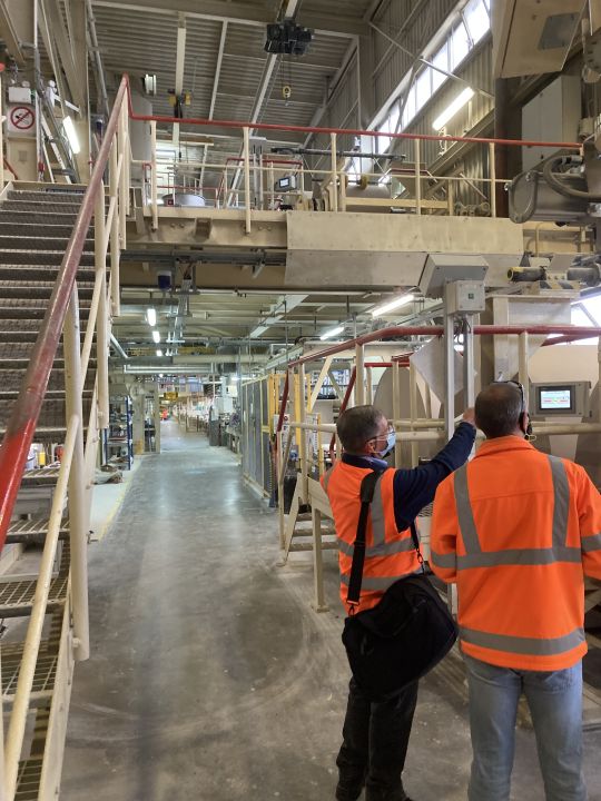 Two engineers in high-visibility vests inspecting industrial drive and transmission machinery on a production line.