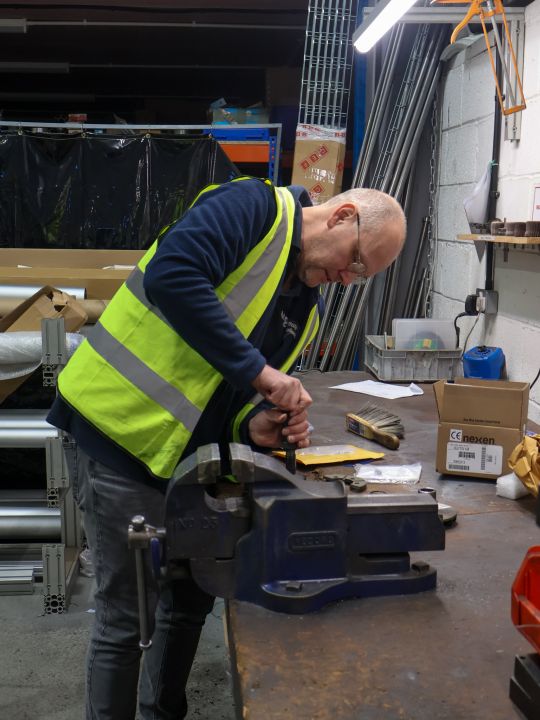 Two engineers in high-visibility vests inspecting industrial drive and transmission machinery on a production line.